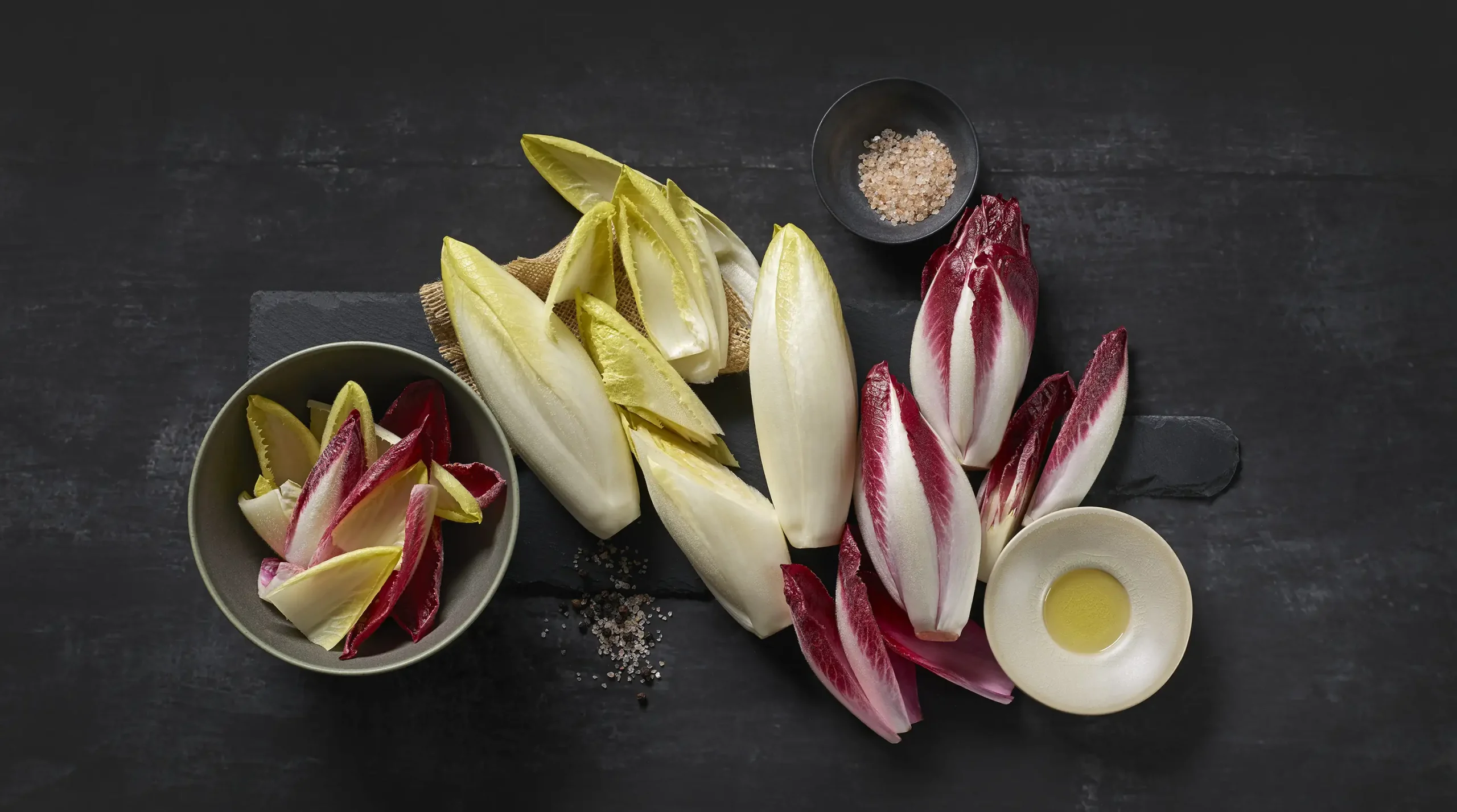 2 fajta cikória (fehér, piros) kulináris módon, sötét háttérrel ábrázolva.