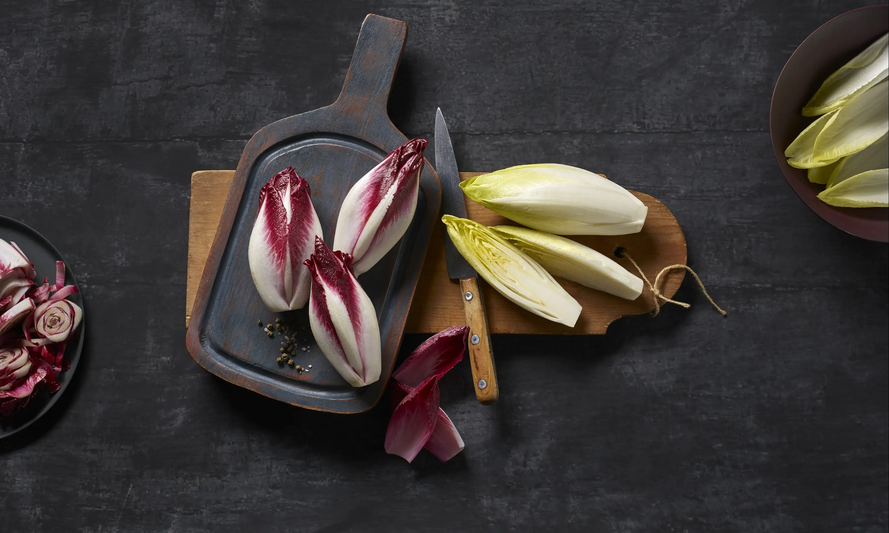 Fehér és piros cikória fadeszkán elrendezve, részben félbevágva